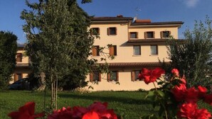 A two-story building with a flat roof, multiple windows, and a visible car parked in front. - B&B Mirò (Pieve di Soligo)