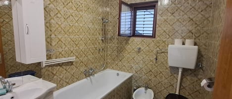 A bathroom with a bathtub, a toilet, a sink, and a window.