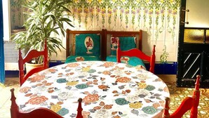 A dining area with a round table, red chairs, a hanging light fixture, and two framed posters on the wall. - Typical Catalan house with sea view (Premià de Mar)