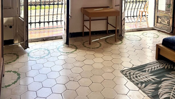 A room with a large open door leading to a balcony with a view of the sea, a small wooden table, a mirror on the wall, and a hexagonal tiled floor. - Typical Catalan house with sea view (Premià de Mar)