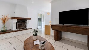 Una sala de estar con chimenea, televisor, mesa de centro y una planta.