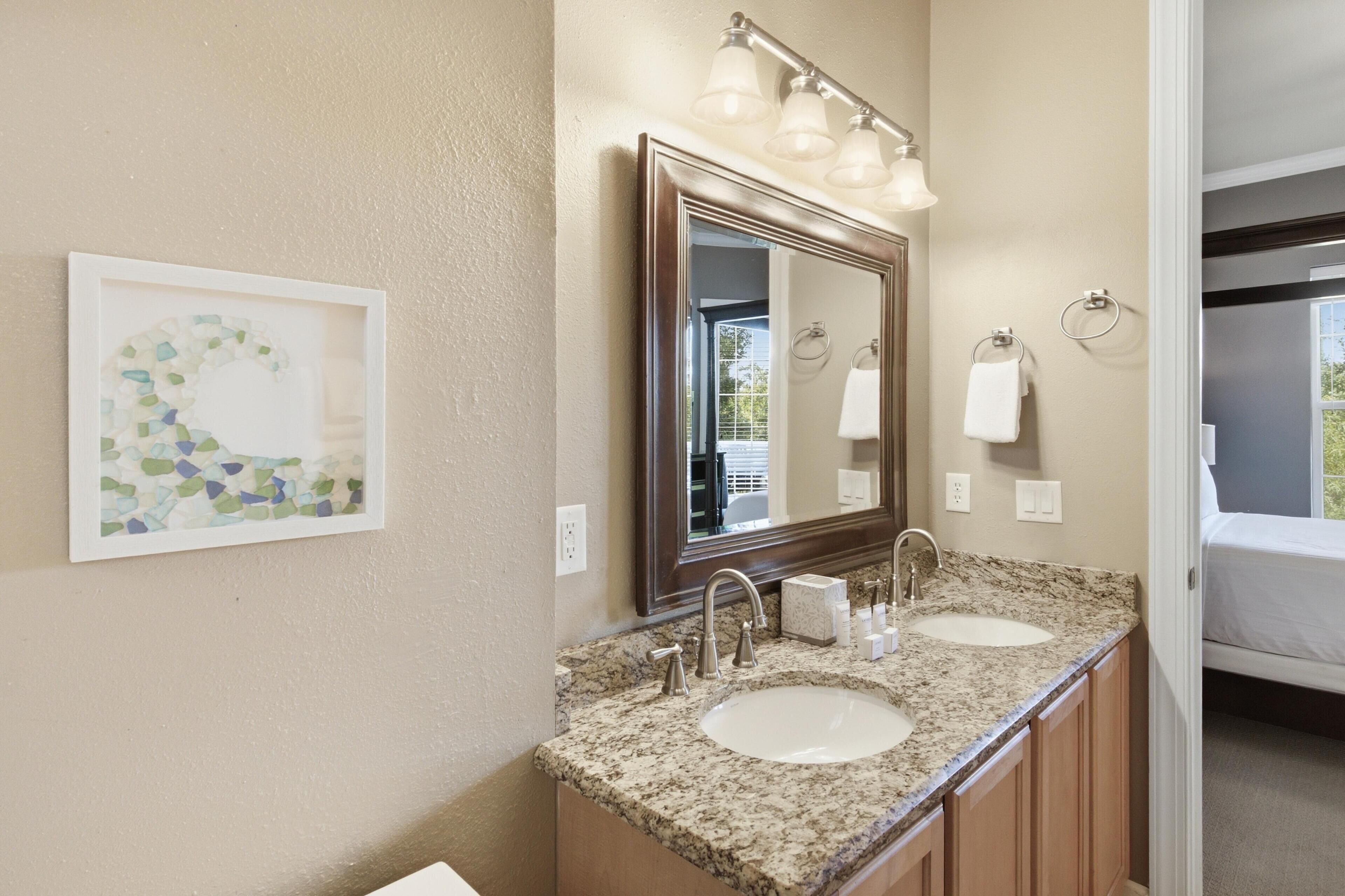 A bathroom with two sinks, a large mirror, and a framed artwork on the wall.