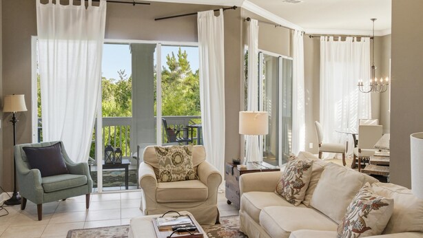 Sala de estar con sofá, sillón y mesa de centro. Se ve un paisaje a través de puertas de vidrio.