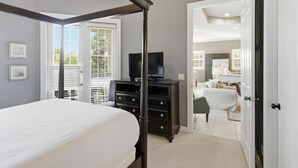 Un dormitorio con cama, cómoda, televisor y puerta que da a otra habitación.