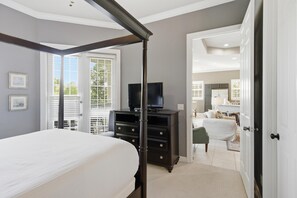 A bedroom with a bed, a dresser, a television, and a door leading to another room. - 2 Bedroom Condo in Crystal Cove (Miramar Beach)