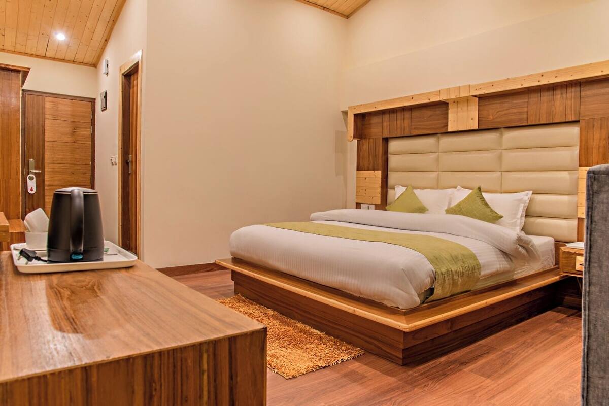 Ein Schlafzimmer mit einem hölzernen Bett, Nachttischen, einer Kaffeemaschine und einem Holzbüro.