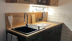 Uma cozinha moderna com armários de madeira, uma pia preta e bancada com utensílios.