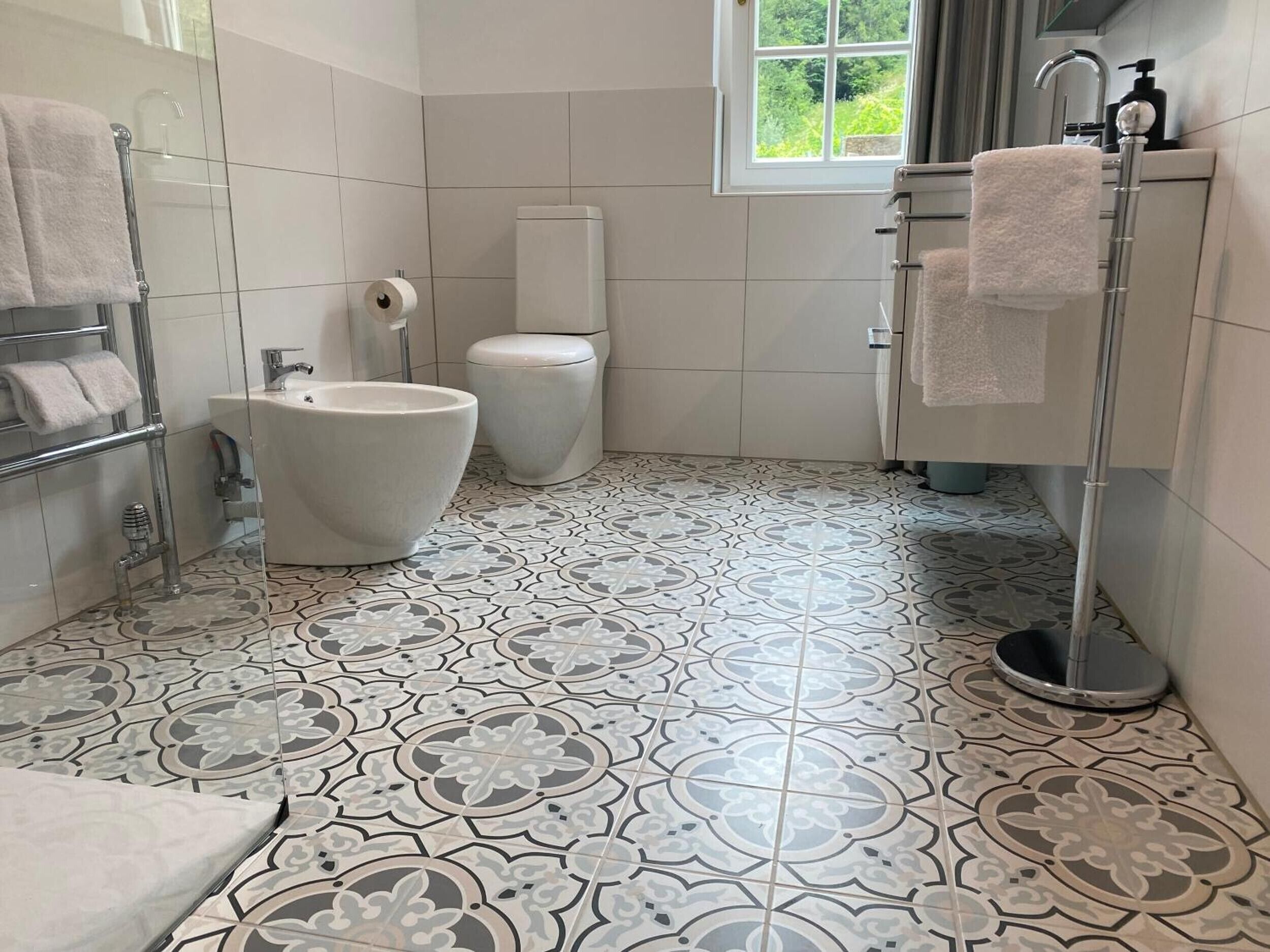 Un baño con inodoro, bidé y un perchero para toallas.