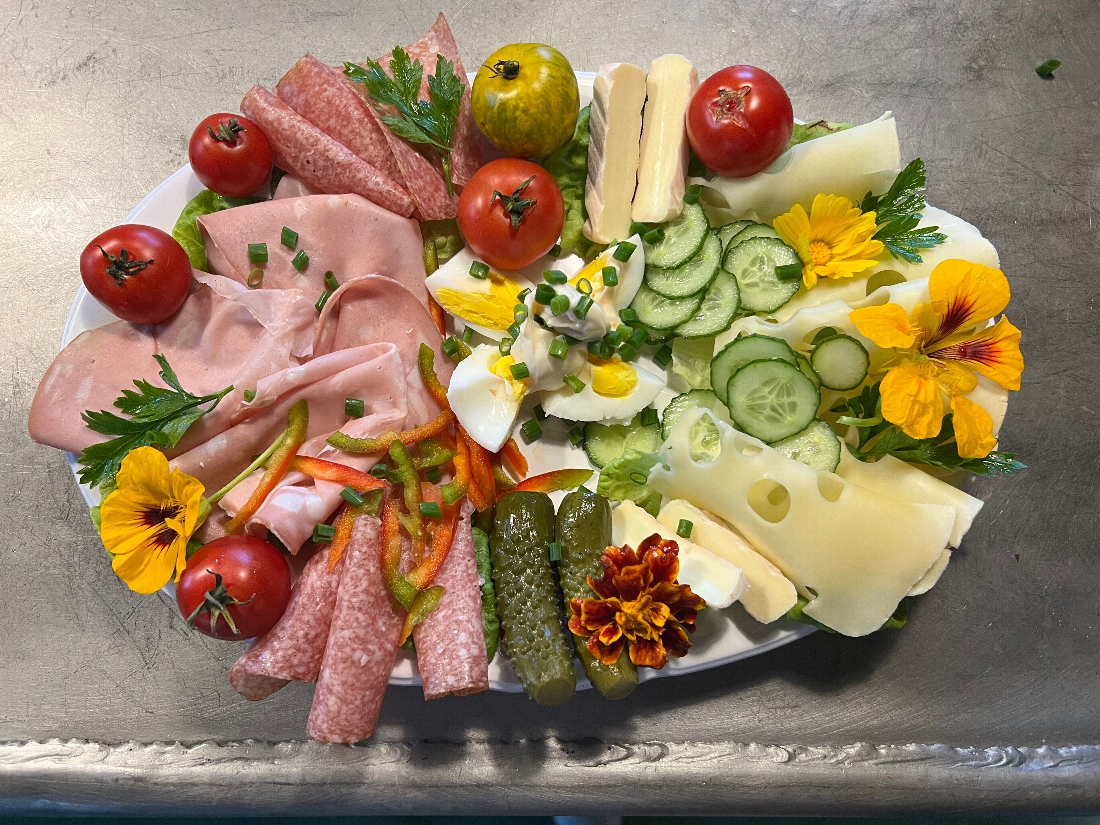 Un piatto assortito di salumi, formaggi e verdure.