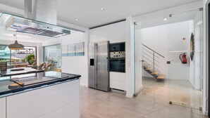 Eine moderne Küche mit einer Glasinsel, Edelstahlgeräten und Blick ins Freie.