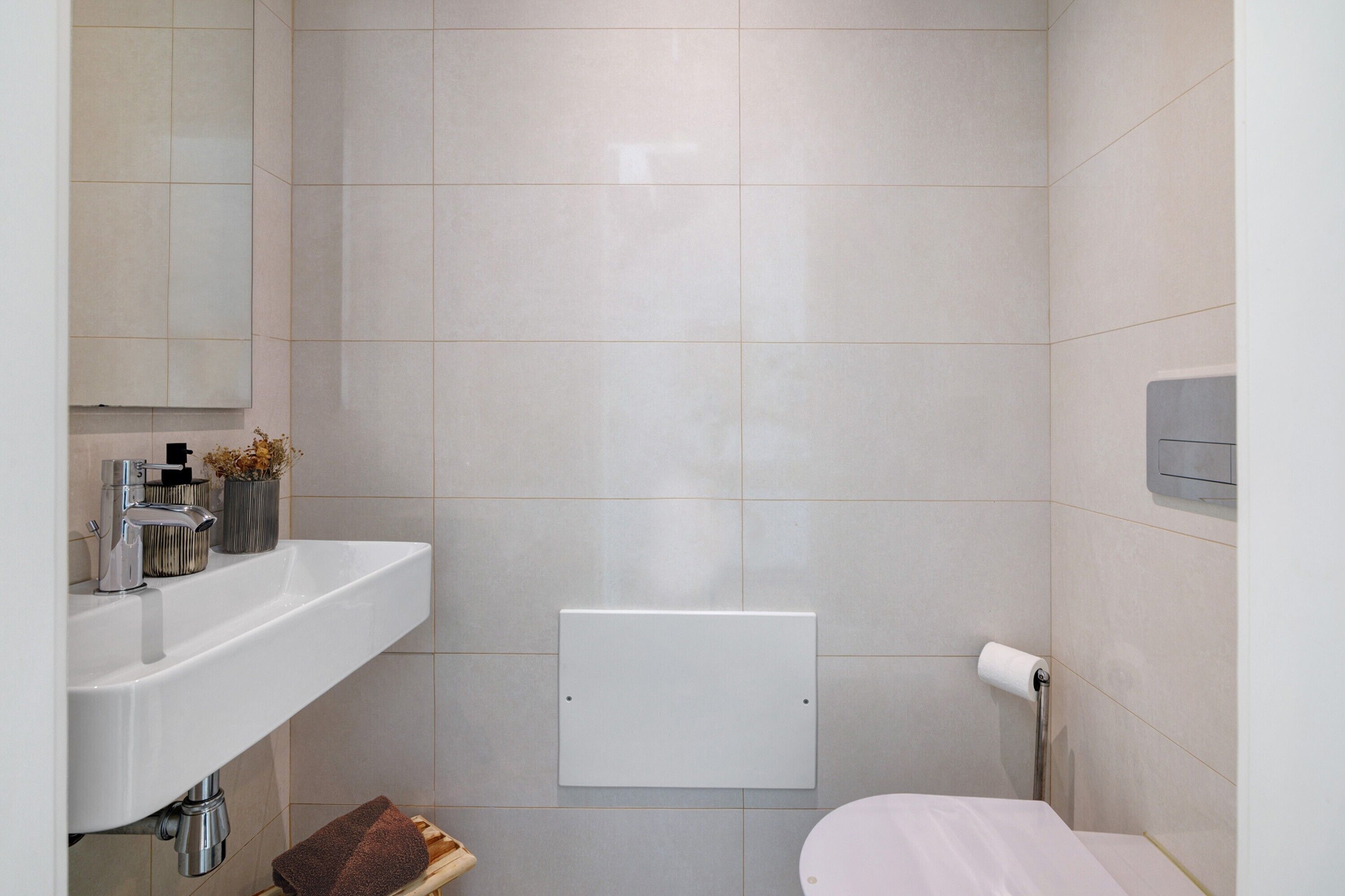 A bathroom with a white sink, mirror, and toilet.