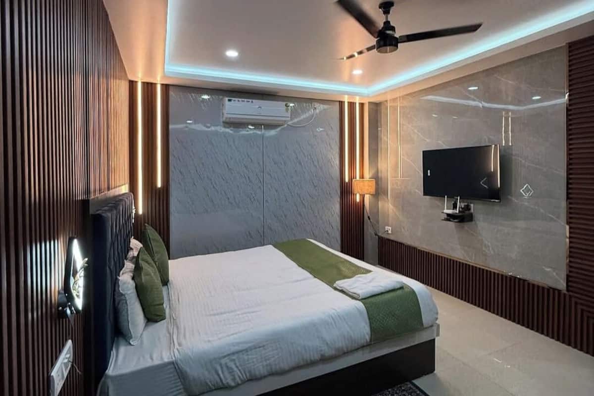 Ein modernes Schlafzimmer mit Bett, Deckenventilator, Klimaanlage, Fernseher und einem gemusterten Teppich.