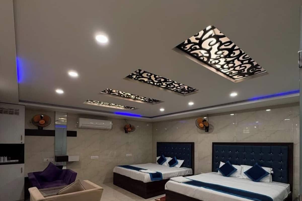 Ein modernes Hotelzimmer mit zwei Betten, einer Sitzecke und einem großen Spiegel.