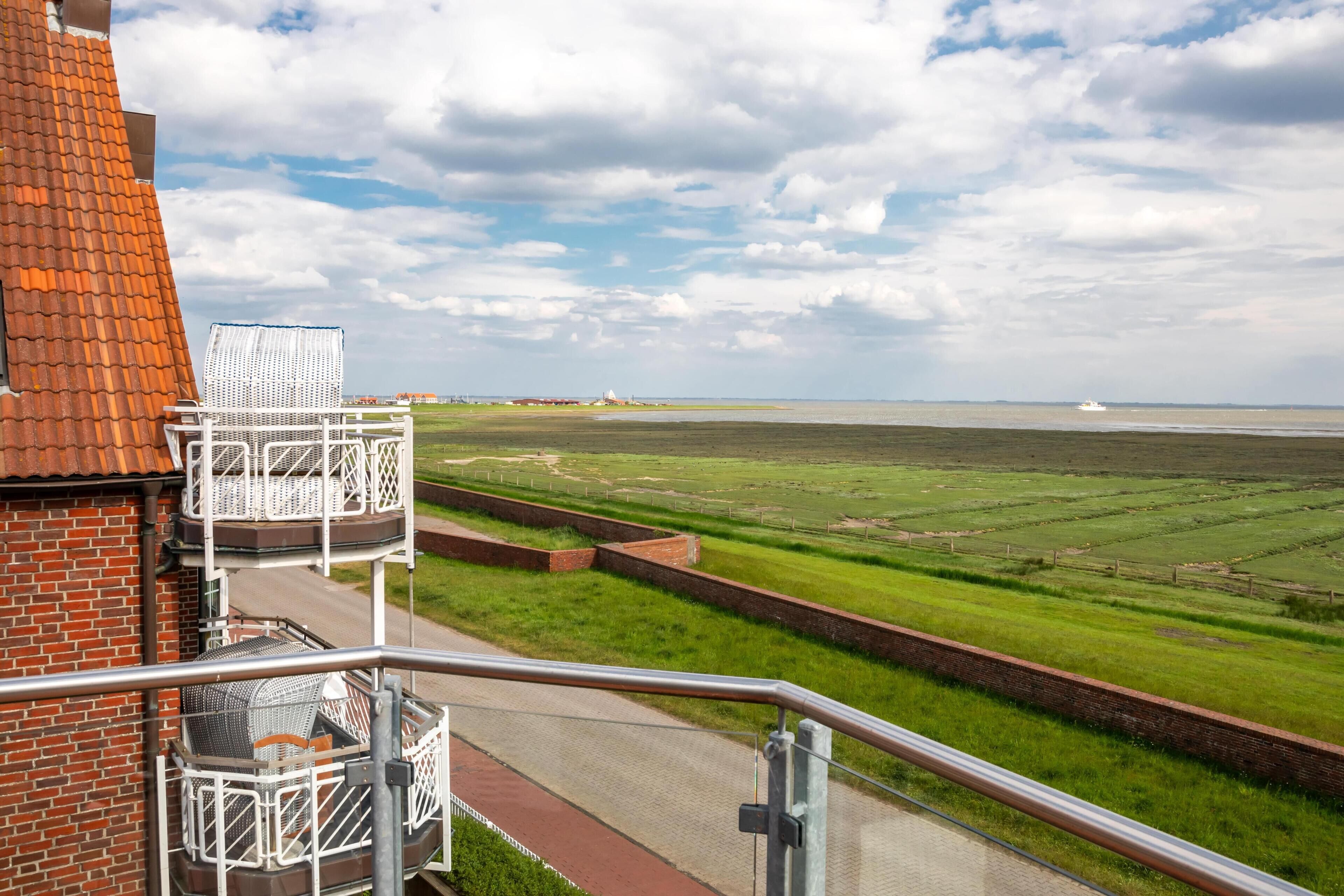 Ein Balkon mit Blick auf eine Küstenlandschaft, inklusive eines Gewässers und einem entfernten Leuchtturm.