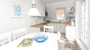 Une cuisine moderne avec des meubles blancs, un plan de travail en bois et un saladier bleu posé sur la table.