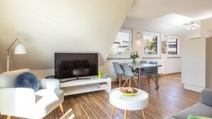 Un salon moderne doté d’un téléviseur à écran plat, d’un coin repas et d’une cuisine.