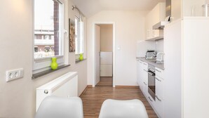Une cuisine moderne avec des armoires blanches, un four encastré et une fenêtre donnant sur les bâtiments environnants.