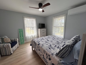 A bedroom with a bed, a chair, a dresser, a television, and a ceiling fan. - Yellow Chairs! Brand New 2-BR in Wells! Book Fall & Winter 2026 & Summer 2027! (Wells)