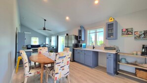 A modern kitchen with a dining area, featuring a central island, cabinets, and a ceiling fan. - Yellow Chairs! Brand New 2-BR.  Book now in Wells for Fall/Winter by the sea! (Wells)