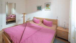 Een slaapkamer met een groot bed, nachtkastjes, een spiegel en kunst aan de muur.