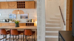 A modern kitchen with a wooden island, bar stools, and a staircase. - Fisherman's Blues – Exclusive Beachfront House with Ocean Views (Arcozelo)