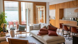 A modern living room with a sofa, chairs, a dining table, and a kitchen area. - Fisherman's Blues – Exclusive Beachfront House with Ocean Views (Arcozelo)