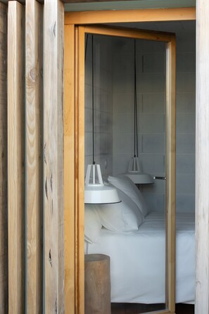 Ein Schlafzimmer mit Holzbett, weißer Bettwäsche und zwei Pendelleuchten.