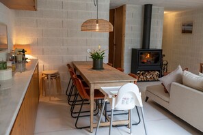 Eine moderne Küche mit Essbereich, einem eingebauten Holzofen und einem weißen Sofa.