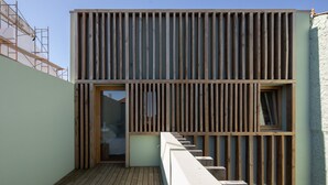 A modern building with a wooden facade, a staircase leading to an upper level, and a visible window. - Fisherman's Blues – Exclusive Beachfront House with Ocean Views (Arcozelo)