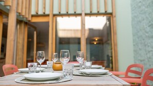 A dining table set with plates, glasses, and cutlery, with chairs around it. - Fisherman's Blues – Exclusive Beachfront House with Ocean Views (Arcozelo)