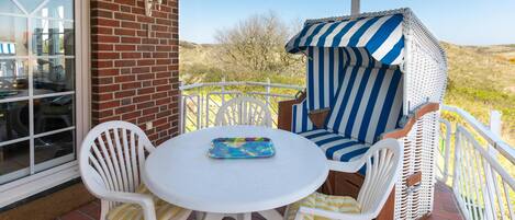 A patio with a round table and white chairs, a striped outdoor seating area, and a brick wall.