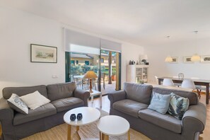 Ein Wohnzimmer mit zwei grauen Sofas, einem kleinen weißen Tisch und einem Essbereich mit Tisch und Stühlen.