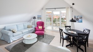 Een moderne woonkamer met een bank, fauteuil, salontafel, eettafel en stoelen.