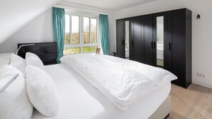 Een moderne slaapkamer met een groot bed, een televisie en een kledingkast.