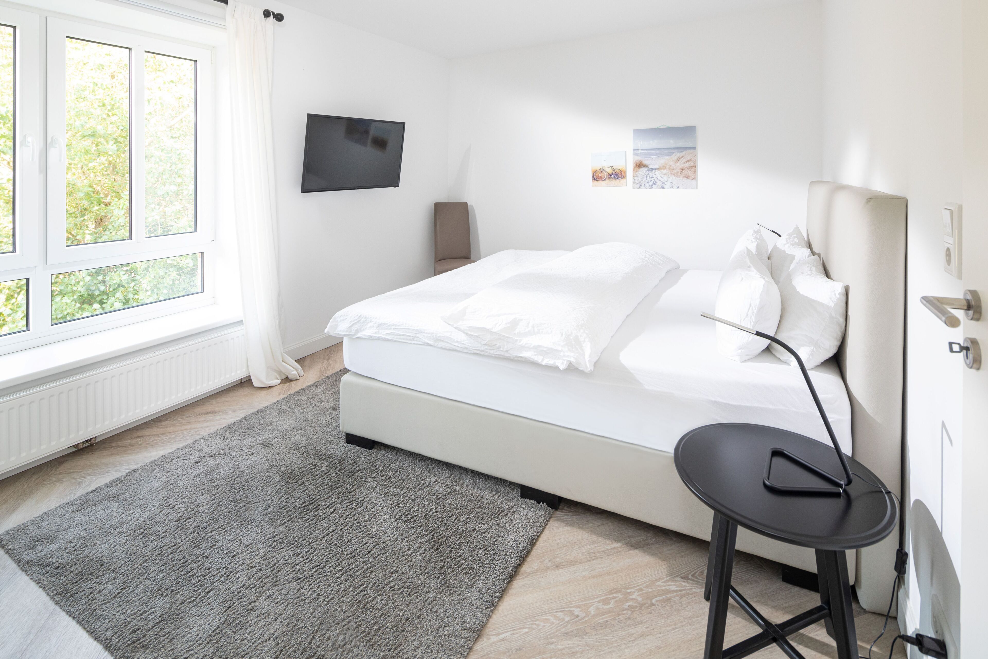 Une chambre à coucher moderne avec un lit, un bureau et un téléviseur fixé au mur.