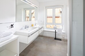 Een moderne badkamer met twee wastafels, een grote spiegel en een raam met uitzicht op een bakstenen gebouw.