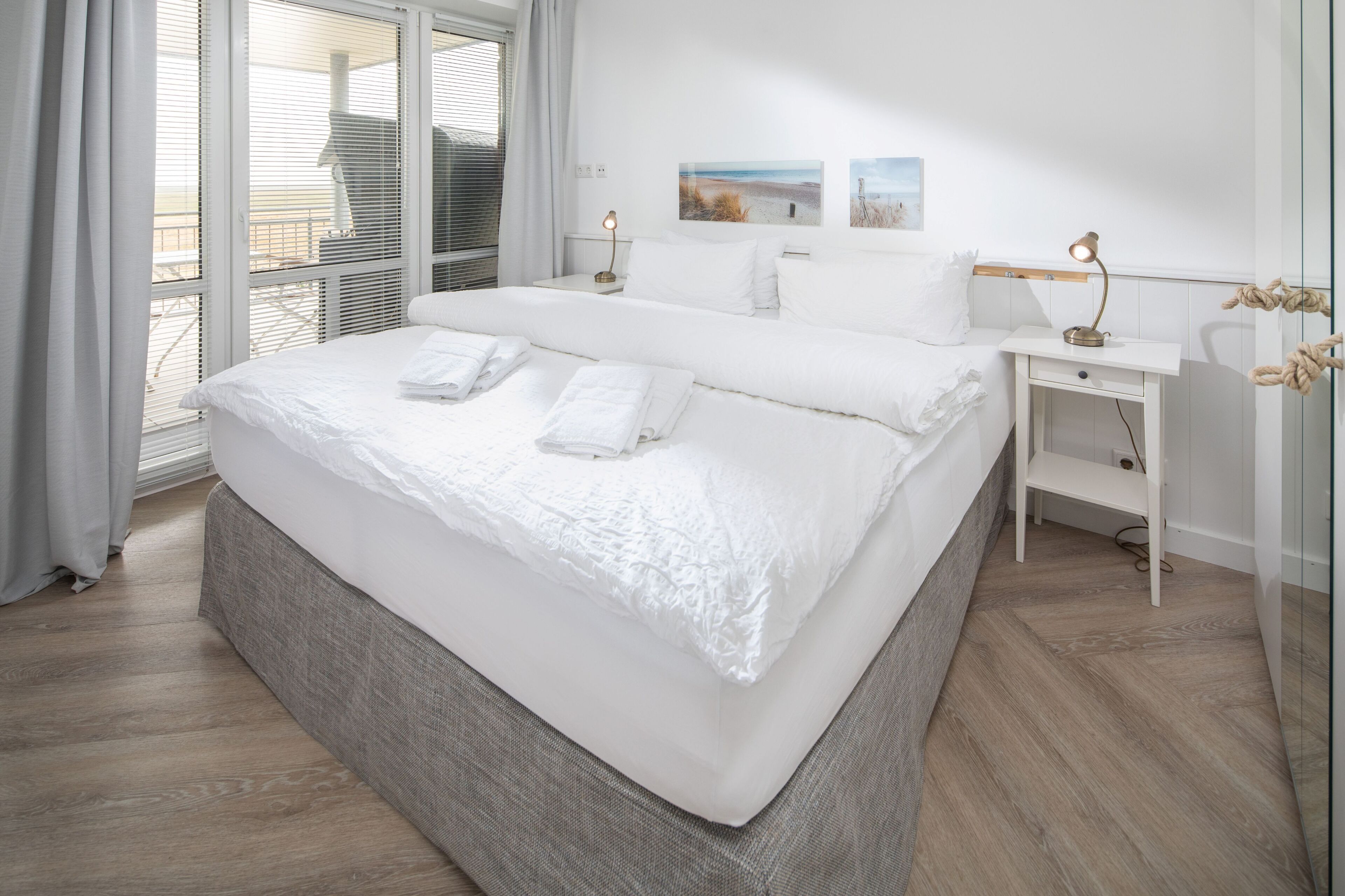 Une chambre d’hôtel avec un grand lit, une table de chevet avec une lampe, une petite table d’appoint et une vue sur l’extérieur.