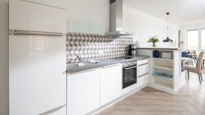 Una cocina moderna con armarios blancos, un salpicadero tipo espiga y un horno empotrado.