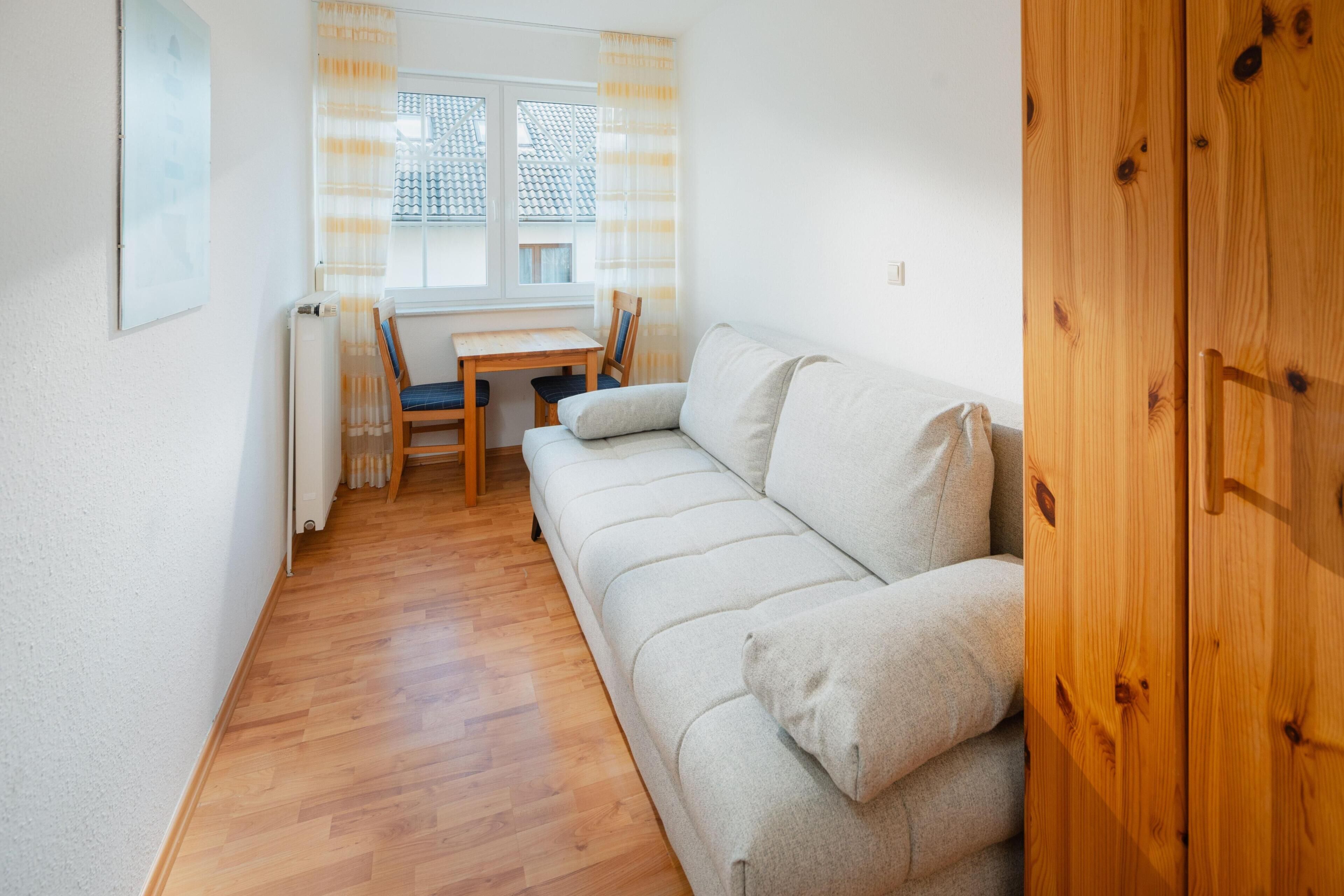 A small, cozy room with a sofa, a wooden table, and a chair.