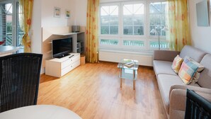 A living room with a TV, sofa, and a glass coffee table. - "Experience an unforgettable vacation at Haus Sanderling Kleeblatt!" (Juist)