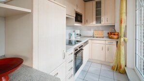 A kitchen with a microwave, oven, and sink. - "Experience an unforgettable vacation at Haus Sanderling Kleeblatt!" (Juist)