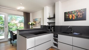 Een moderne keuken met een ruim kookeiland, een eethoek met tafel en stoelen, en uitzicht door een glazen deur.