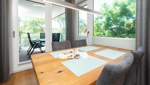 Een moderne vergaderruimte met een houten tafel, grijze stoelen en grote ramen met uitzicht op groen.