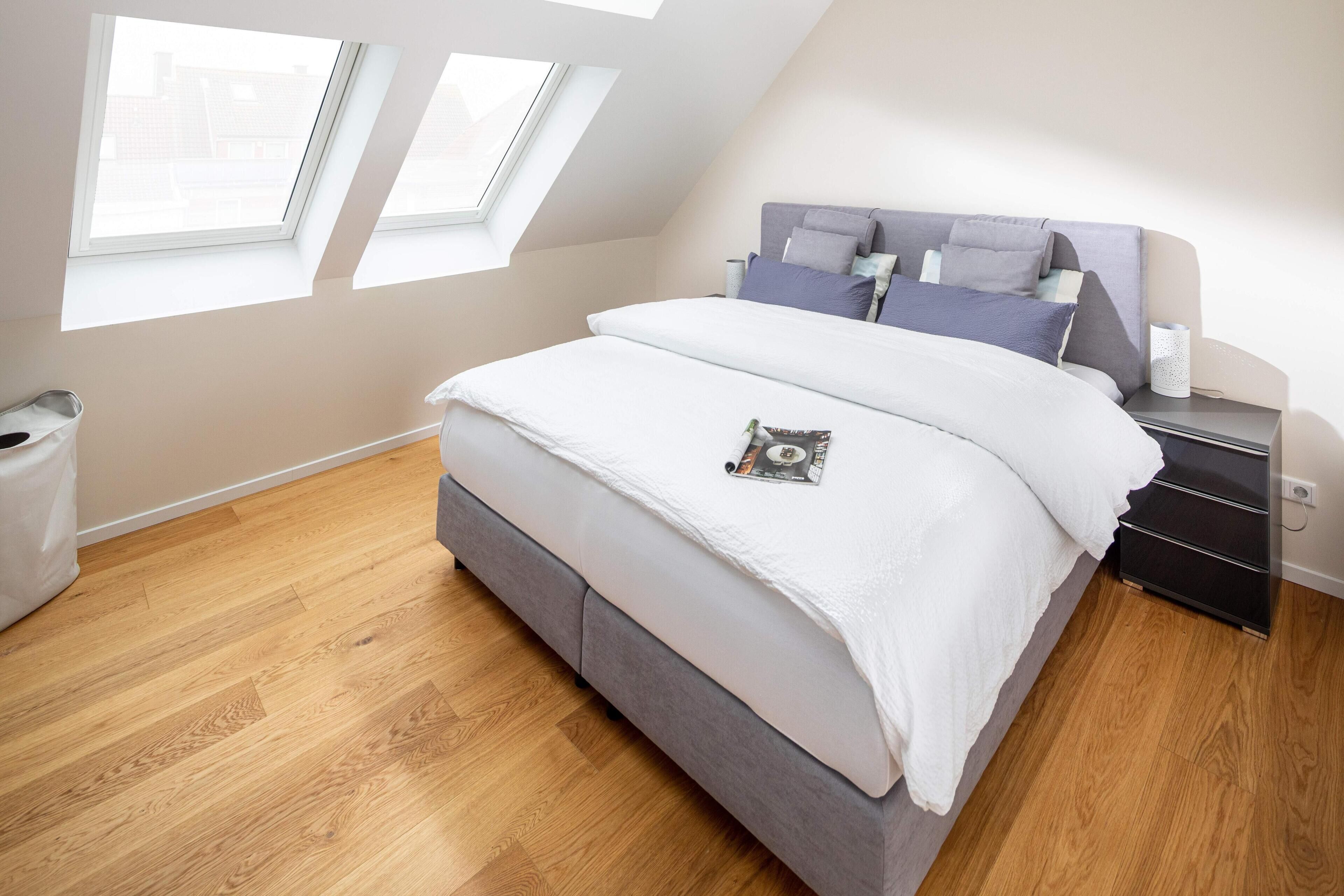 Una camera da letto con un letto, un comodino, una finestra e un lucernario.