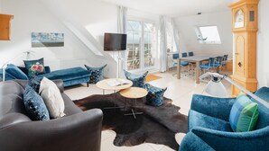 Ein modernes Wohnzimmer mit einer Couch, einem Couchtisch und einem Essbereich mit Stühlen.