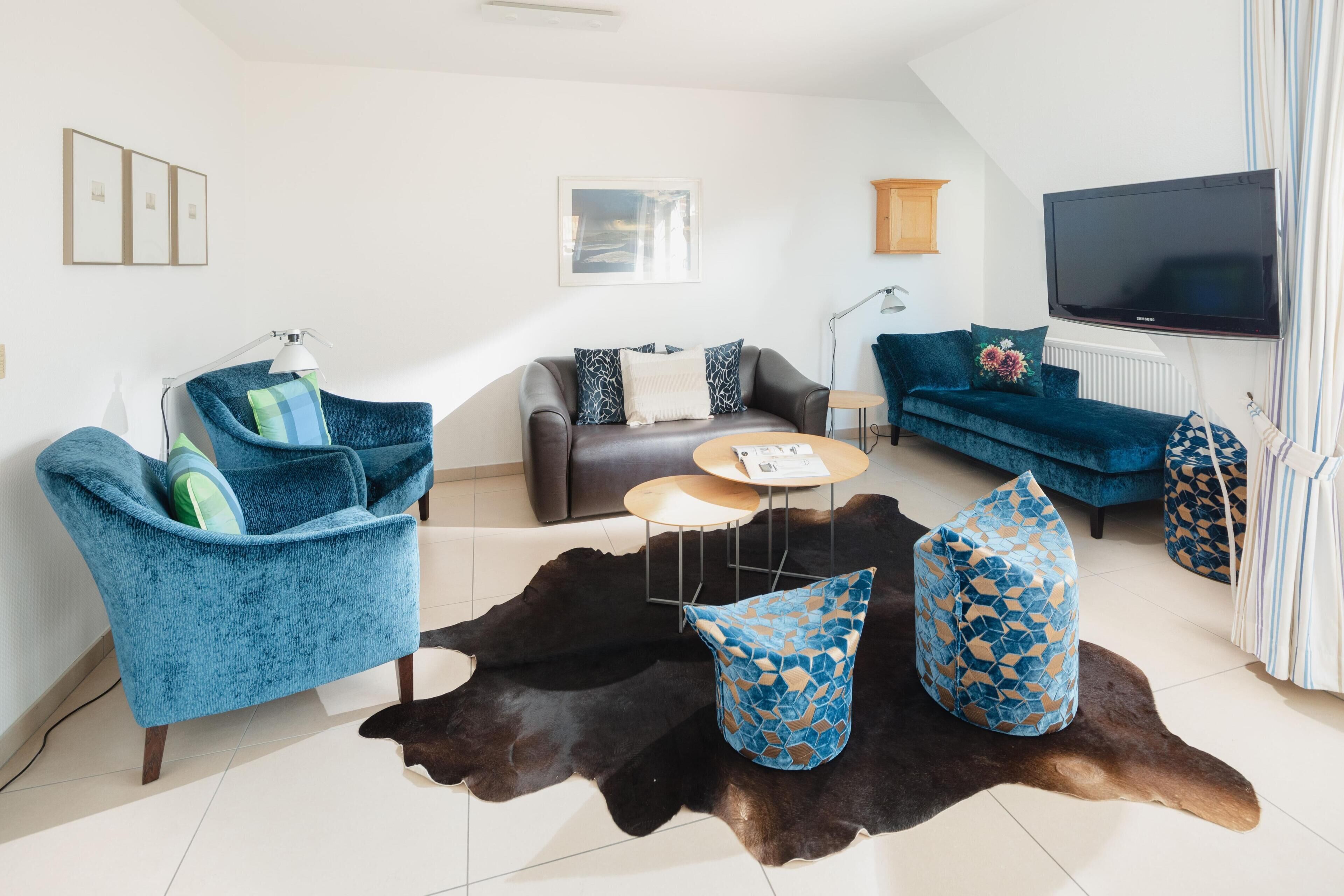 A modern living room with a sofa, armchairs, a coffee table, and a television.