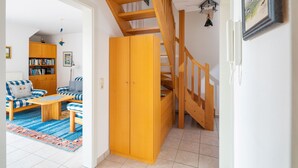 Een kamer met een houten trap, een zithoek, een houten kast en een boekenkast.