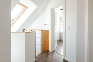 Ein schmaler Korridor mit Oberlicht, einer Holztreppe und einer Tür zu einem anderen Raum.