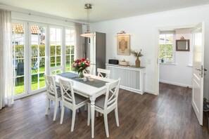A dining area with a white table and chairs, a vase of flowers, and a radiator.