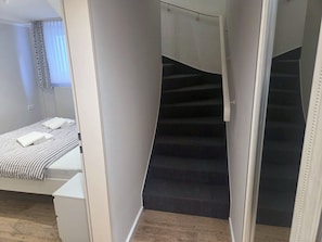 A modern bedroom with a bed, a bathroom, and a staircase. - "Idyllic vacation apartment Seute Deern Kajüte - your perfect retreat on the (Juist)